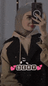 a woman in a hijab is taking a picture of herself with her phone