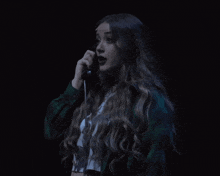 a woman with long hair talking on a phone in a dark room