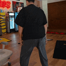 a man in a black shirt stands in a room with a pepsi cooler in the background