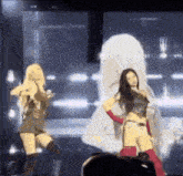 a couple of women are dancing on a stage in front of a large screen .