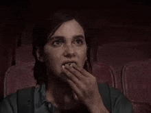 a woman is eating popcorn in a theater .