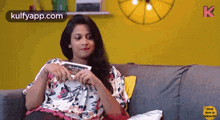 a woman is sitting on a couch with a book in her hand .