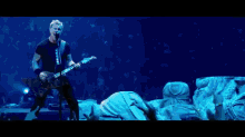 a man singing into a microphone while playing a guitar in front of a crowd
