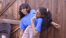a man and a woman are standing next to each other in front of a wooden wall