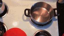 a pot sits on top of a stove with a red hat on it