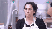 a woman in an apron is making a funny face in front of a sink with the words bake off argentina on the bottom right