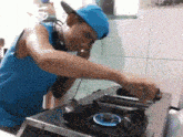 a man wearing headphones and a blue hat is cooking on a stove .