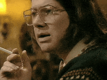 a woman wearing glasses is smoking a cigarette with her mouth open