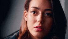 a close up of a woman 's face with a leather jacket on