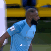 a soccer player wearing a blue etihad shirt