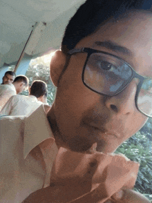 a young man wearing glasses is eating a piece of bread