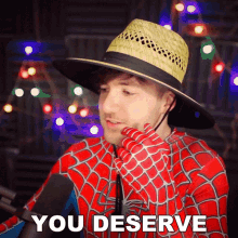 a man in a spiderman costume says " you deserve " in front of a microphone