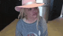 a woman wearing a pink hat and a blue sweater is sitting on the floor .