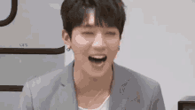 a young man in a suit is laughing with his eyes closed and his mouth open .