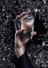 a woman with blue eyes is holding a broken mirror