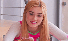a young woman is sitting at a table holding a piece of cake in her hand .