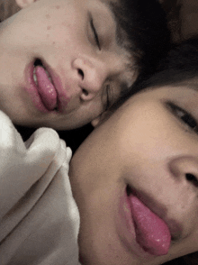 two young boys sticking their tongues out while sleeping