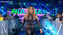 a woman is walking on a stage in front of a crowd with the word nia on it .