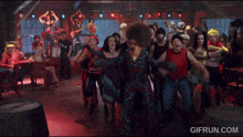 a group of people are dancing in a room with the website gifrun.com at the bottom of the screen