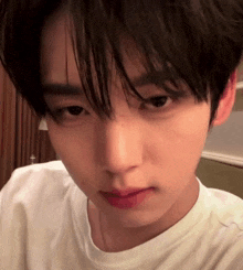 a close up of a young man 's face with a white t-shirt on .
