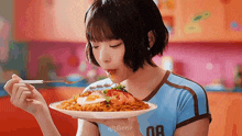 a girl wearing a blue shirt with the number 08 on it is eating noodles with a fork