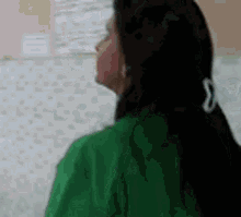 a woman in a green shirt is looking up at the sky .