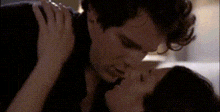 a man and a woman are kissing each other in a room .