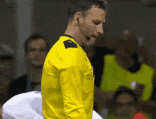 a man in a yellow shirt has a microphone on his ear