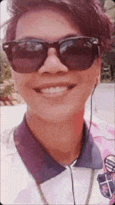 a man wearing sunglasses and a pink shirt is smiling for the camera