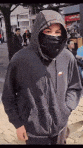 a man wearing a black nike hoodie and a black face mask