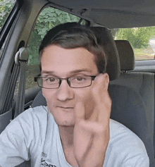 a man wearing glasses is sitting in a car and giving a middle finger