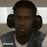 a man wearing headphones and a microphone has #fimovie written on the bottom right