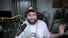 a man with a beard and headphones is standing in front of a microphone in a room .
