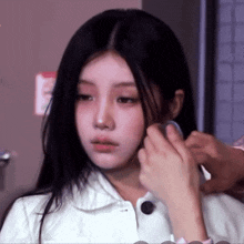 a woman in a white jacket is getting her hair done by a man .