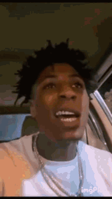 a man with dreadlocks is sitting in a car with his mouth open .