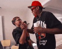 a man wearing a dennis rodman shirt holds a cup in his hand