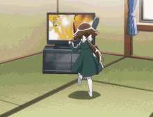 a girl in a green dress is dancing in front of a flat screen television