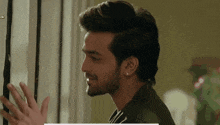 a man with a beard and earrings is looking out a window and smiling