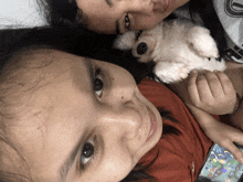 a little girl is laying on a woman 's lap holding a white dog
