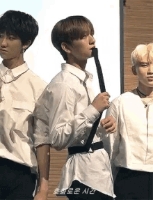 a group of young men are standing next to each other and one of them is wearing a white shirt and tie .
