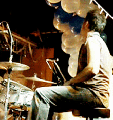 a man playing drums with balloons hanging from the ceiling
