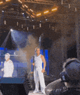 a man holding a microphone stands on a stage in front of a crowd