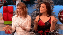 two women are sitting next to each other in front of a christmas tree on a hallmark channel show .