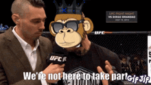 a man in a suit is talking to a monkey wearing sunglasses and a crown that says we 're not here