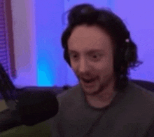 a man wearing headphones and a microphone is sitting in front of a microphone .