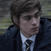 a young man in a suit and tie is looking at the camera