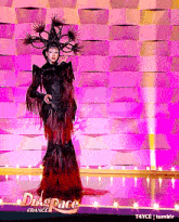 a drag queen is standing on a stage in front of a wall that says drag space