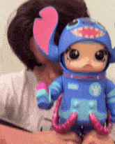 a person is holding a stitch doll with the letter w on the chest