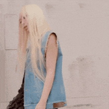 a woman with blonde hair is wearing a blue vest
