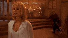 a woman in a white shirt is standing in front of a man in a dark room .